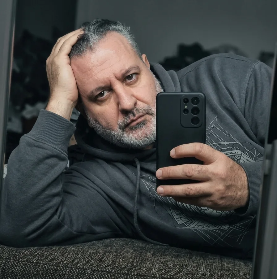 Jorge Dias fazendo uma selfie diante de um espelho, usando moletom cinza