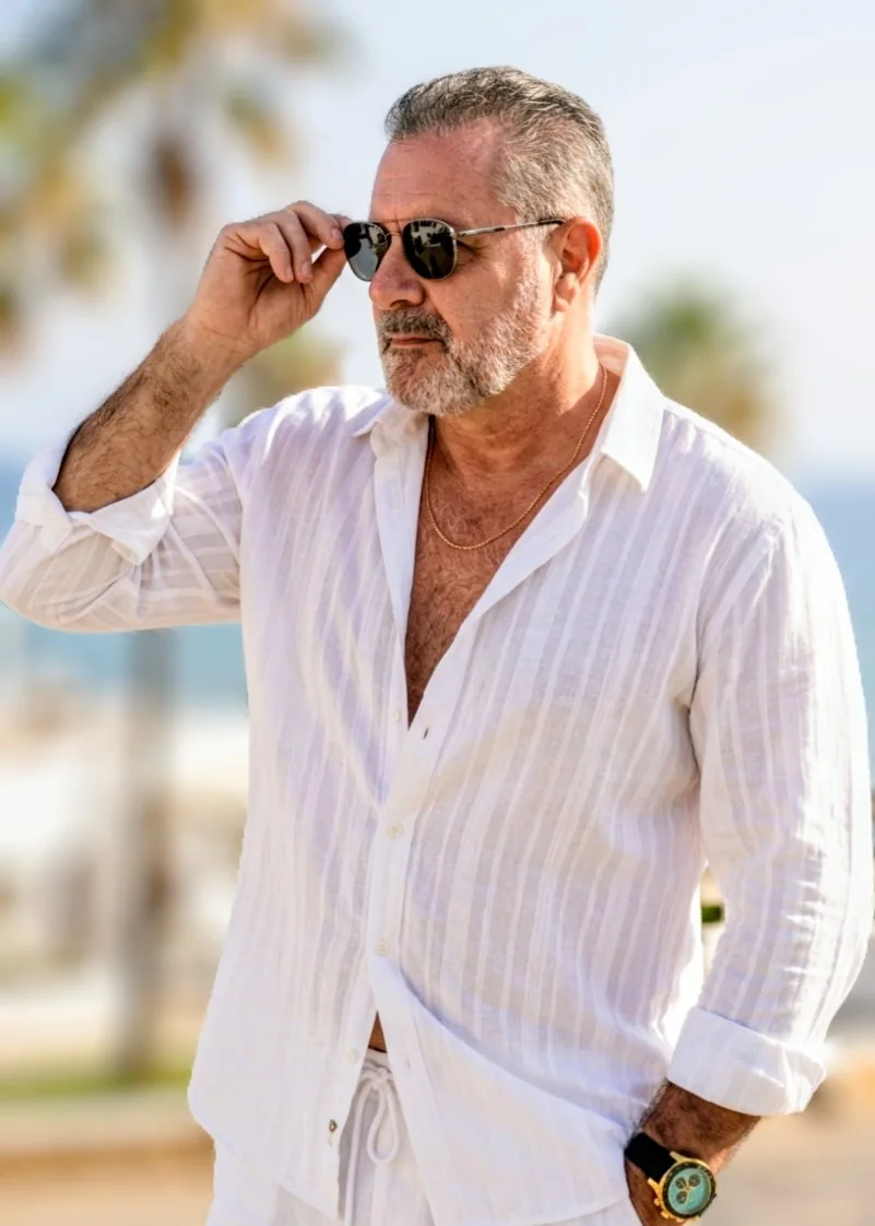 Jorge Dias ao ar livre, usando camisa branca e óculos escuros