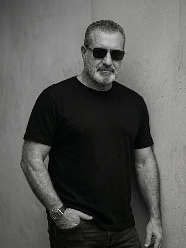 Jorge Dias em preto e branco, usando óculos escuros e camiseta preta