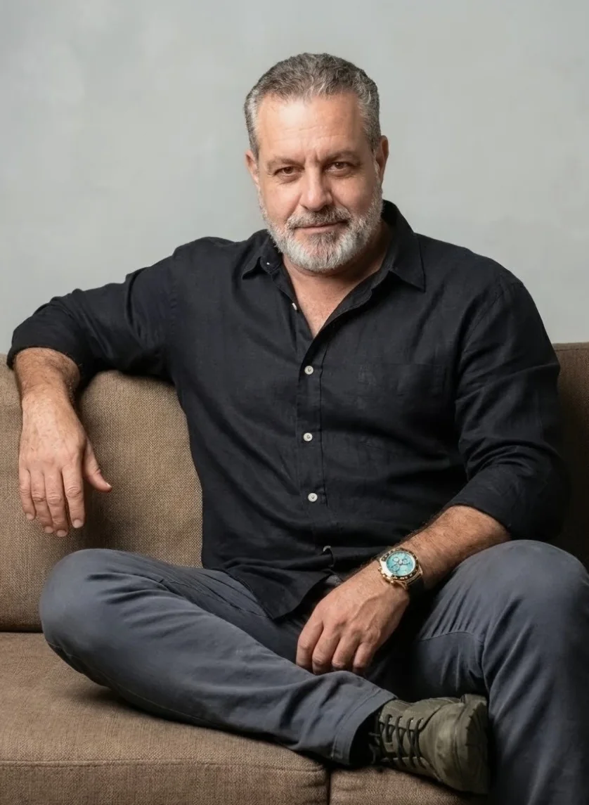 Jorge Dias sentado em um sofá, usando camisa preta